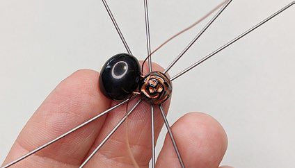 Wire ends from black and rose bead component are bent at 90-degree angles outward from the main direction of the wire